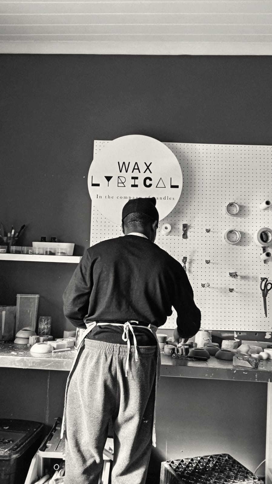 Black and white: a maker at the pegboard wall, shaping candle forms